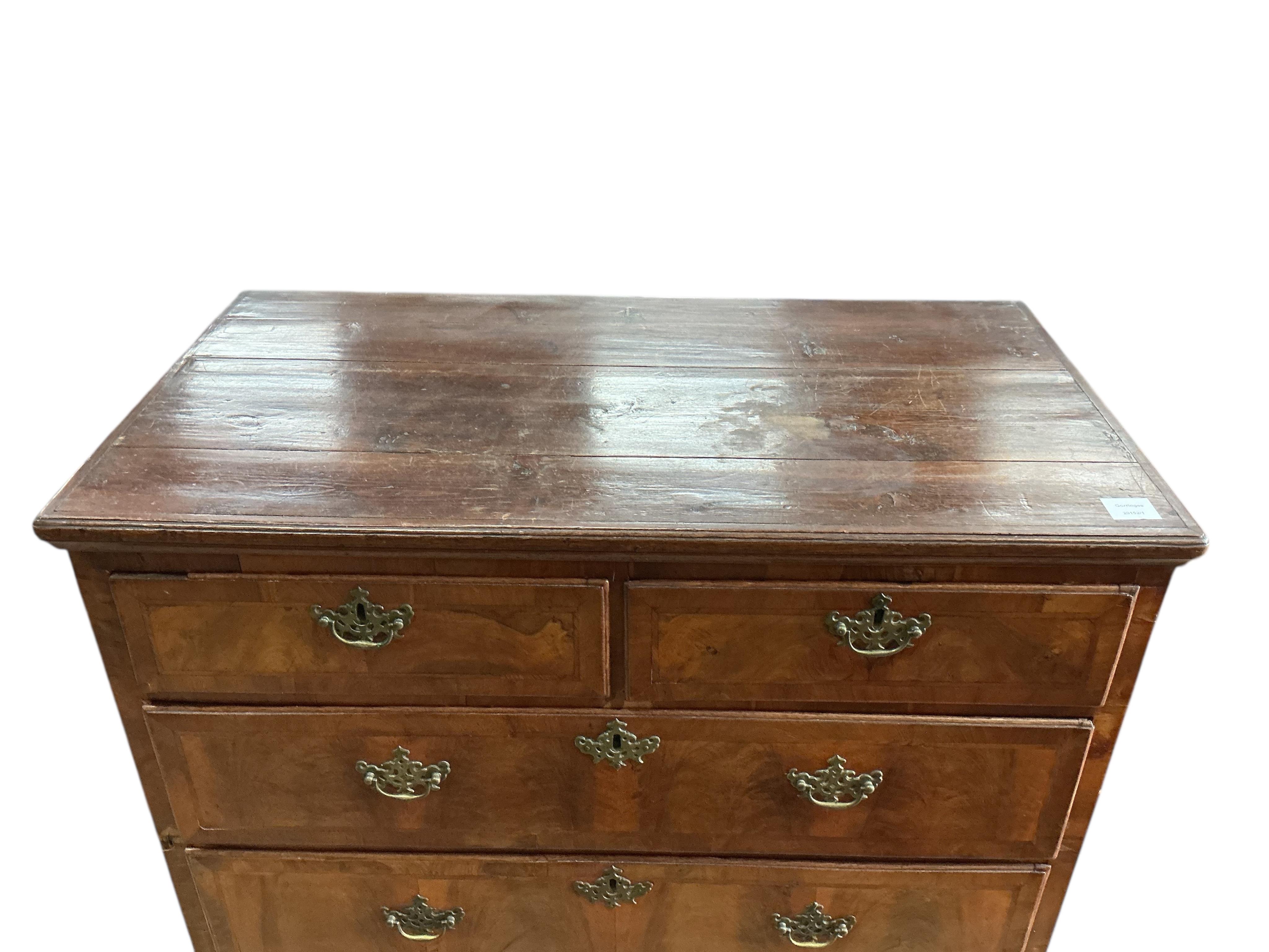An early 18th century feather banded walnut and pine two section chest of drawers, on later bracket feet and with losses, width 96cm, depth 52cm, height 135cm